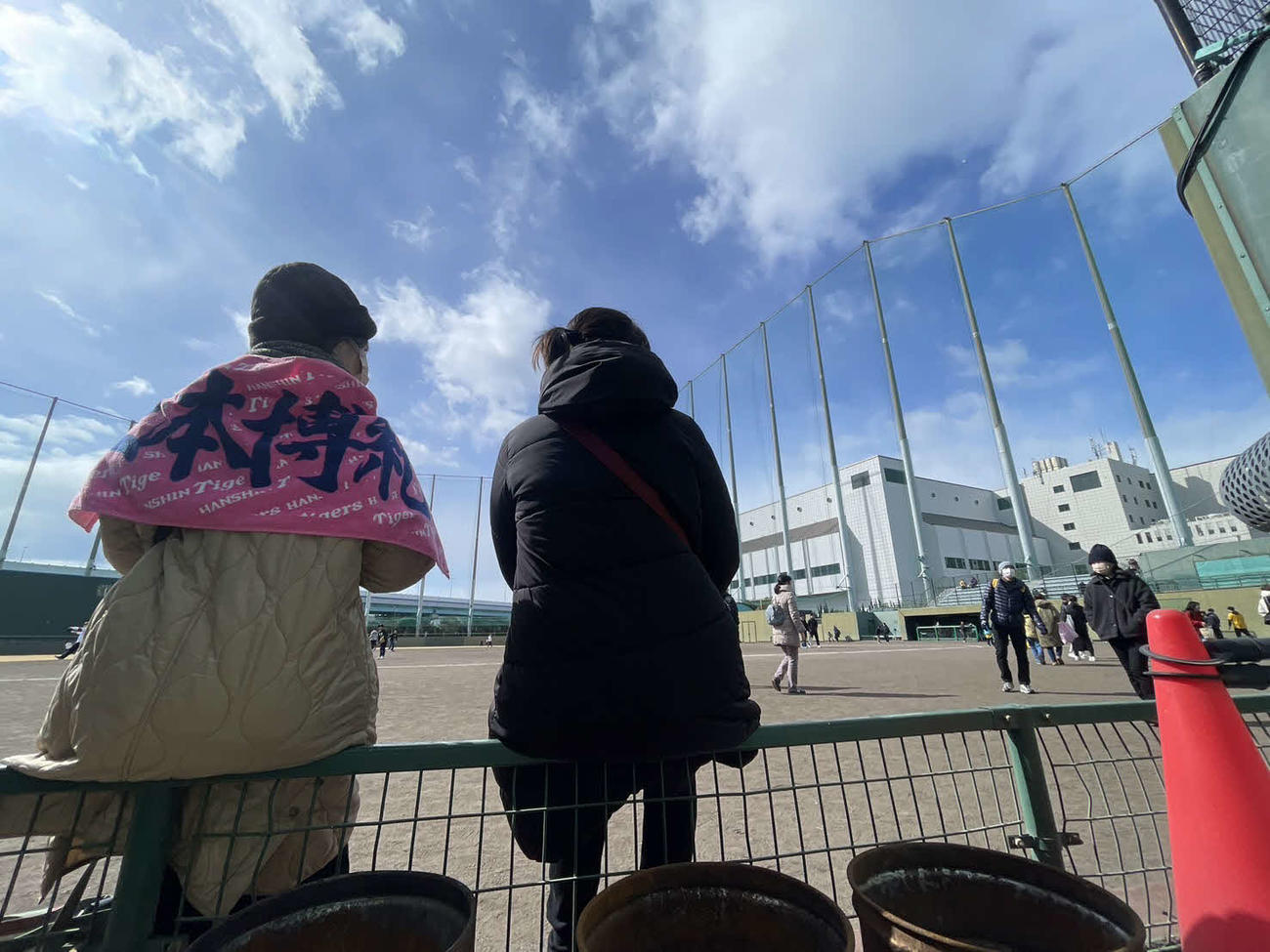 1月末まで約30年使われた阪神鳴尾浜球場の三塁側カメラ席前のファンスに腰掛けるファン（撮影・中島麗）