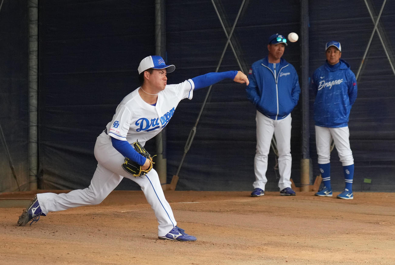 ブルペンで投球練習をする金丸（左）奥・左から井上監督、落合2軍監督（撮影・森本幸一）