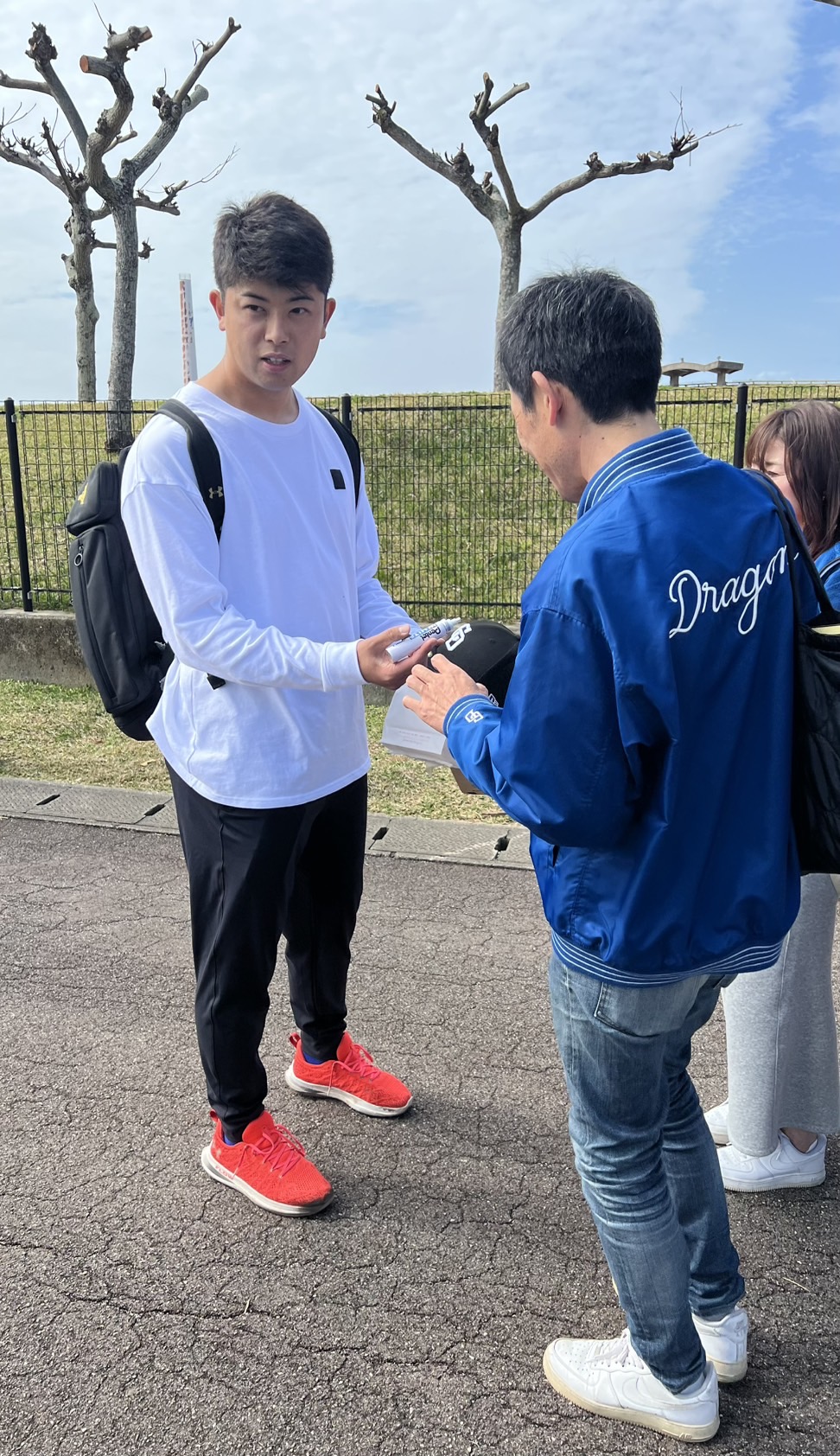 中日松山（左）は休日練習後にファンにサインをする