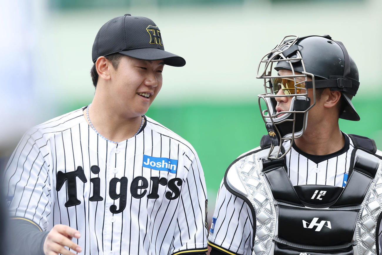 阪神対楽天　1回表を投げ終え、笑顔で阪神坂本（右）と言葉を交わす門別（撮影・前田充）