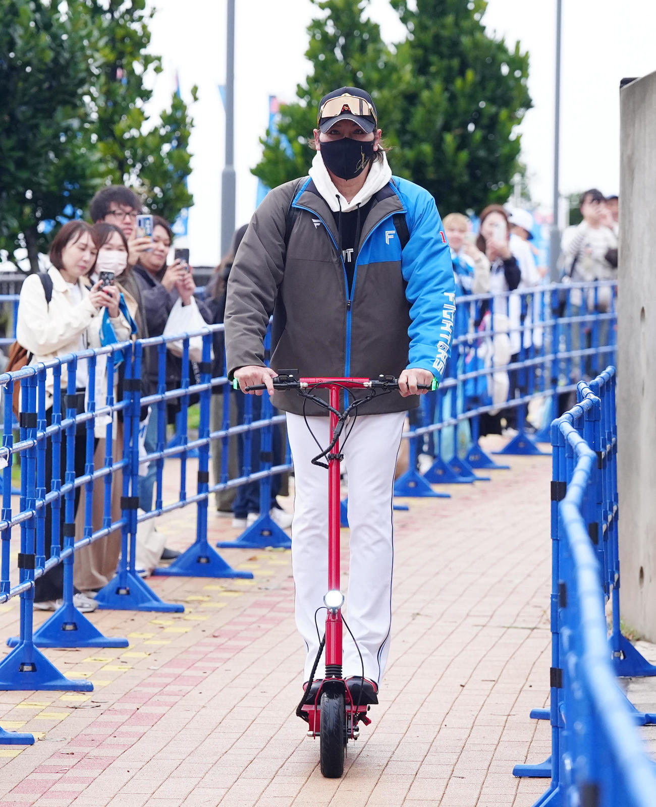 電動キックボードに乗って、スタジアム入りする日本ハム新庄監督（撮影・江口和貴）