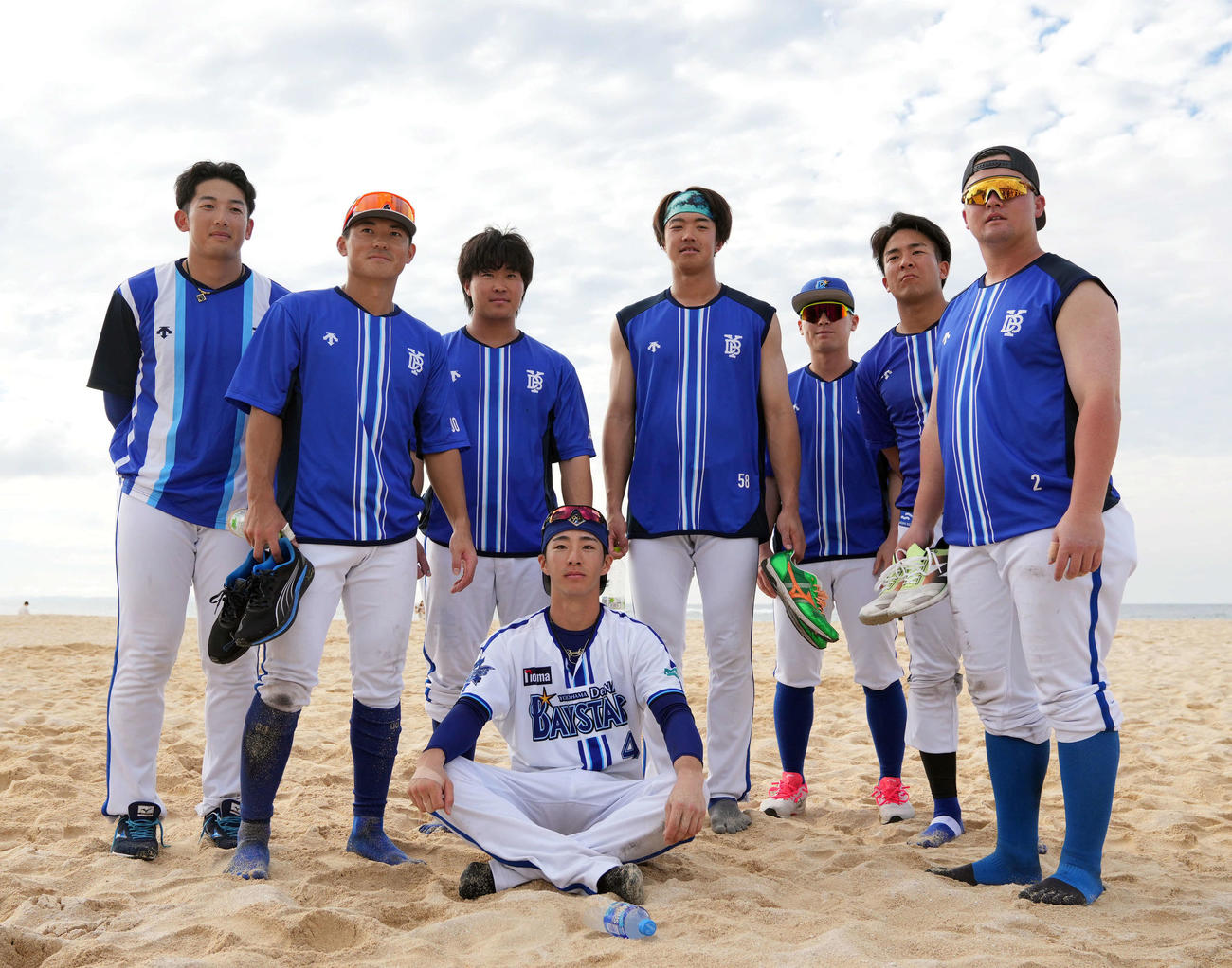 24年2月4日、DeNA沖縄・宜野湾春季キャンプ　砂浜トレを終え記念撮影をする度会隆輝（前列）らナイン。後列左から山本祐大、林琢真、石上泰輝、梶原昂希、柴田竜拓、勝又温史、牧秀悟（撮影・たえ見朱実）