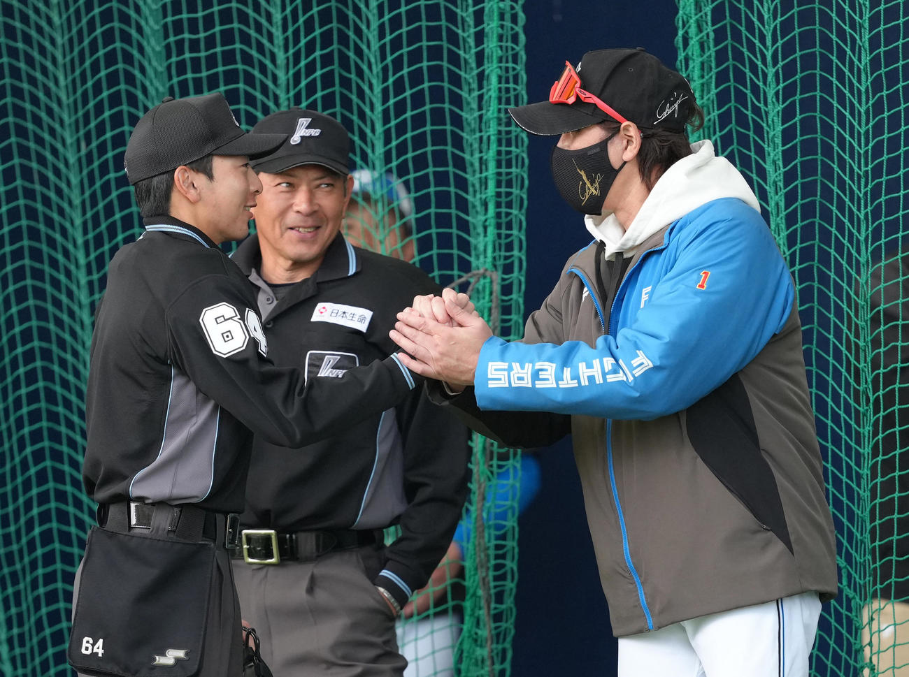 ブルペンで審判団と握手を交わす日本ハム新庄監督（右）（撮影・足立雅史）
