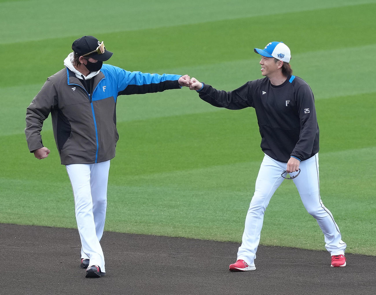 練習前、日本ハム宮西（右）と会話を交わしタッチを交わす新庄監督（撮影・足立雅史）