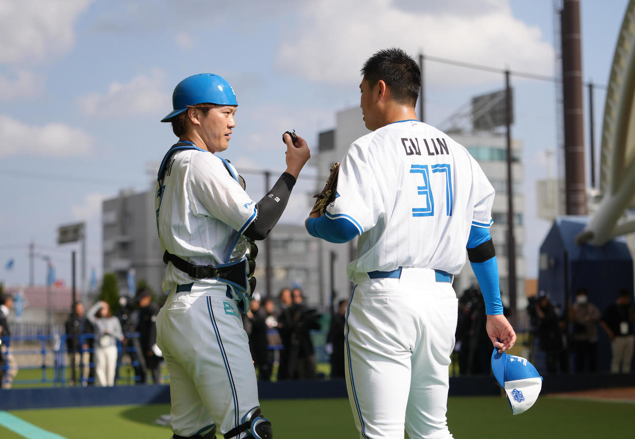 ブルペン投球を終え、会話を交わす日本ハムの古林（右）と伏見（撮影・足立雅史）