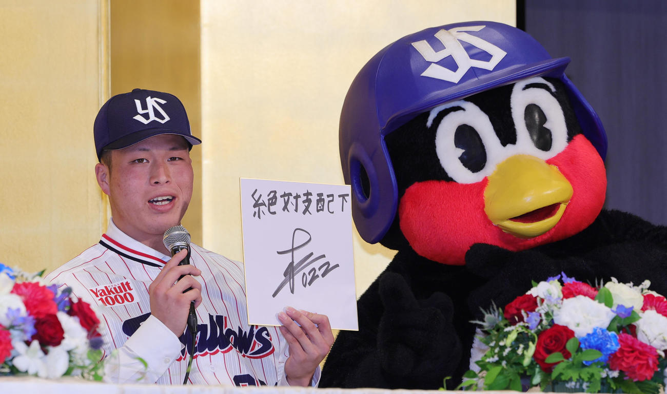 ヤクルトの新入団選手発表で、目標を「絶対支配下」と記す松本。右はつば九郎（撮影・野上伸悟）