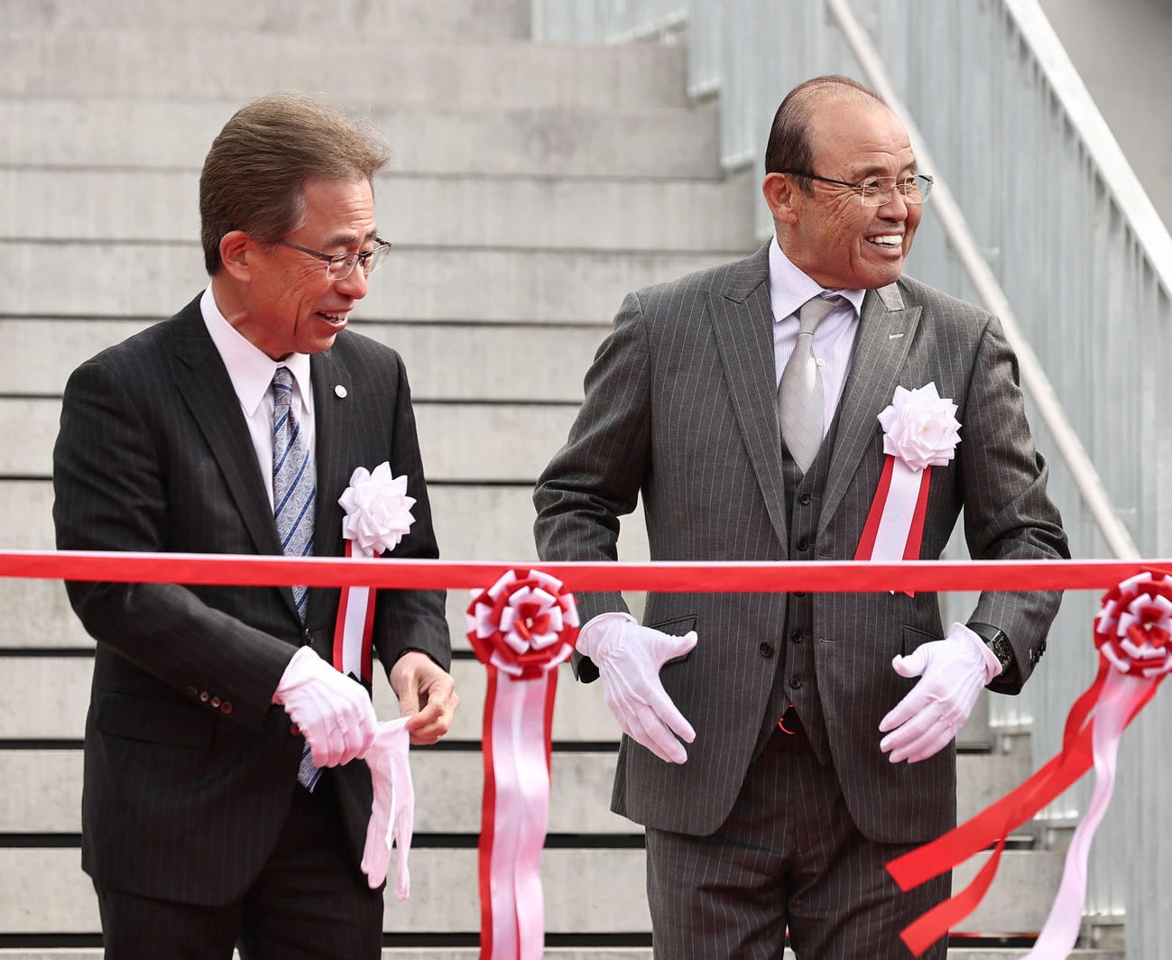 阪神2軍の新本拠地となる日鉄鋼板SGLスタジアム尼崎が完成しテープカットの前、笑顔を見せる阪神岡田オーナー付顧問。左は粟井球団社長（撮影・西尾就之）