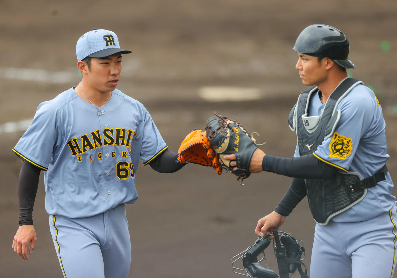 2軍練習試合・日本ハム対阪神　4回裏に登板した阪神石井（左）は無失点に終え捕手栄枝とタッチをかわす（撮影・上山淳一）