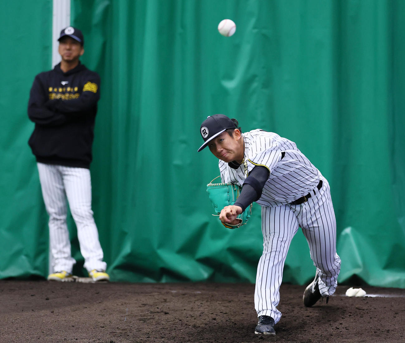 ブルペンで藤川監督（左）が見つめる中、投球練習をする伊原（撮影・藤尾明華）