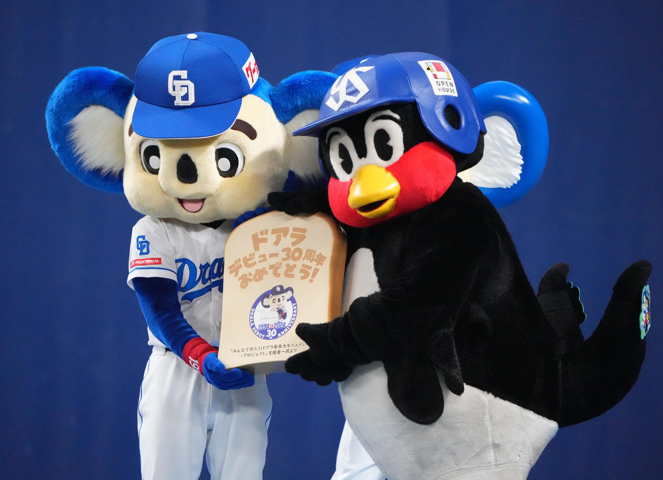 2024年5月　イベントで等身大モニュメント支援者一同からの食パン型プレートをつば九郎から受け取るドアラ（左）