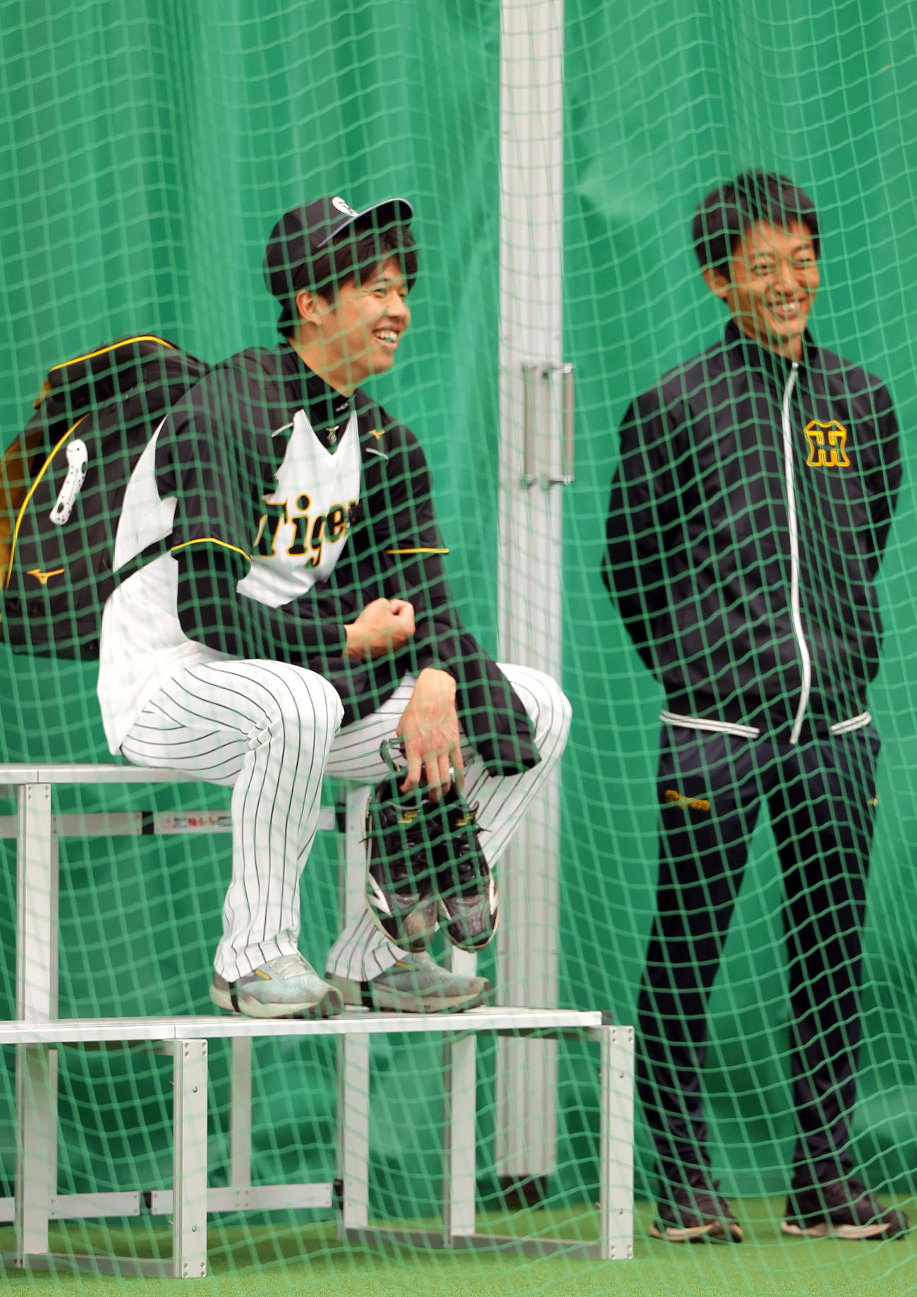 阪神才木（左）はブルペンで座り笑顔を見せる（撮影・上山淳一）