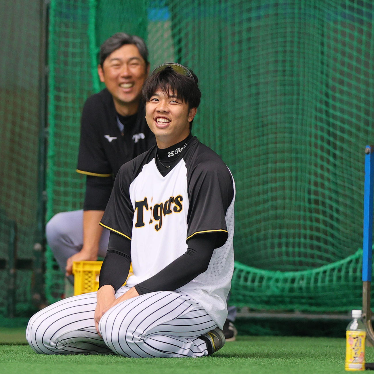 阪神才木浩人（手前）は室内でリラックスした表情を見せる。奥は金村投手コーチ（撮影・上山淳一）