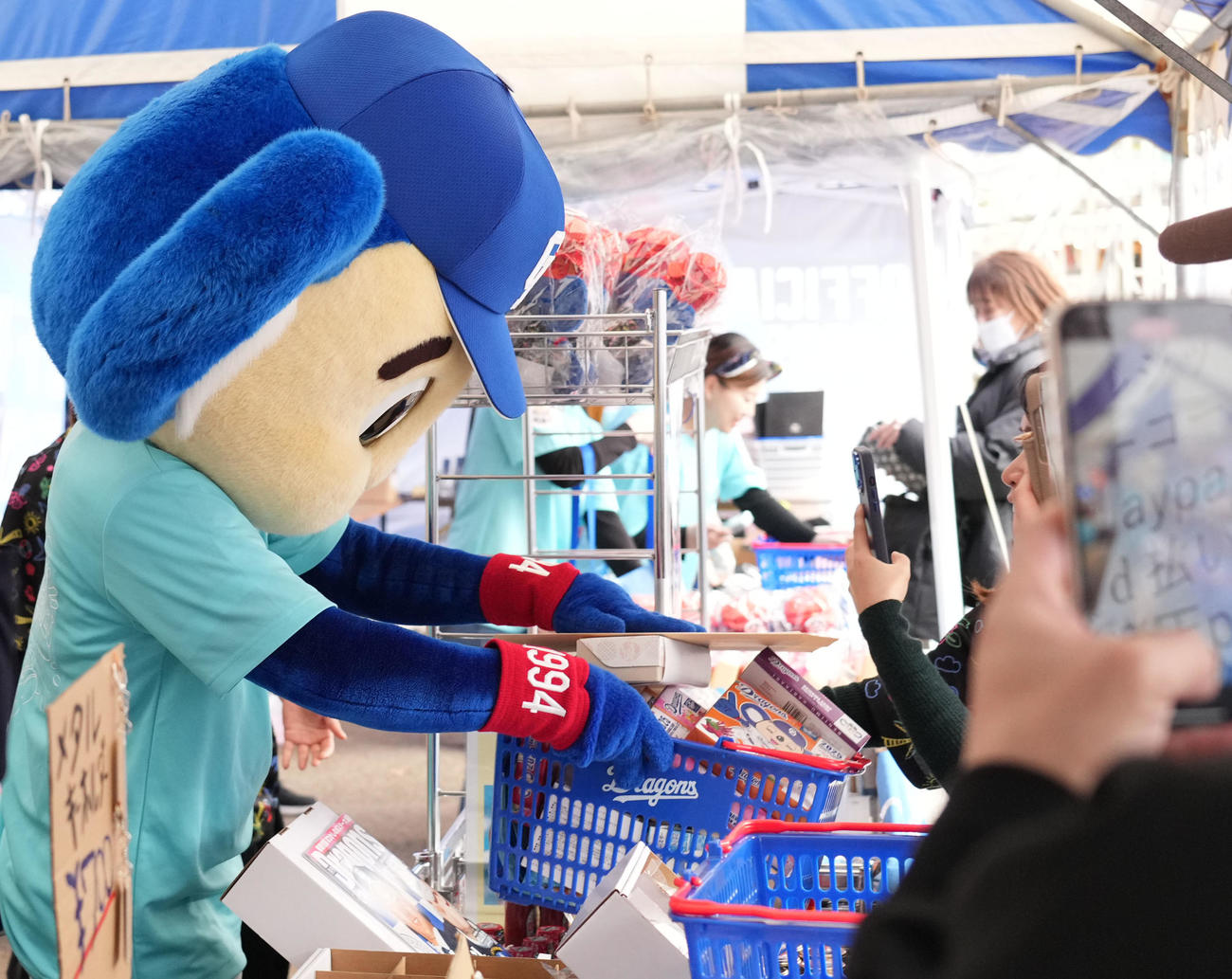 中日対ロッテ　グッズ売り場でオススメ商品をかごに詰めお客さんに渡すドアラ（撮影・森本幸一）