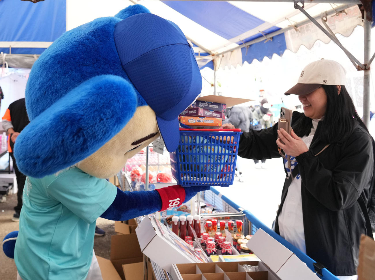 中日対ロッテ　グッズ売り場でオススメ商品をかごに詰めお客さんに渡すドアラ（撮影・森本幸一）