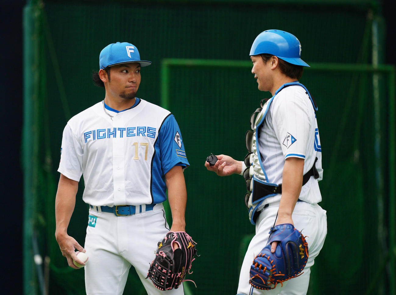 ブルペン投球を終えた日本ハム伊藤（左）は伏見と会話を交わす（撮影・足立雅史）
