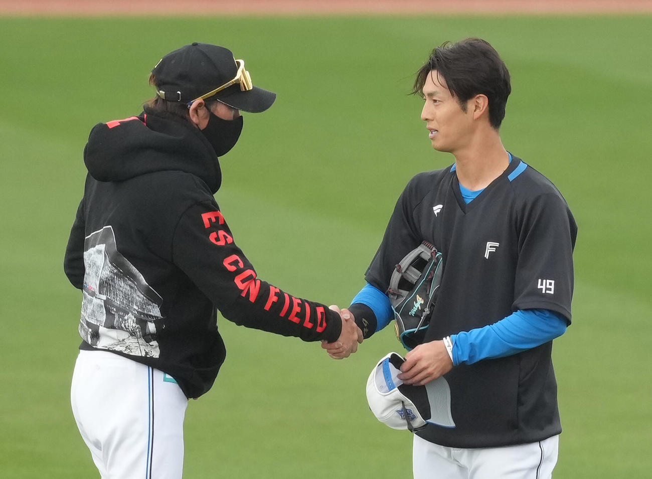 練習中、日本ハム若林（右）と握手を交わす新庄監督（撮影・足立雅史）