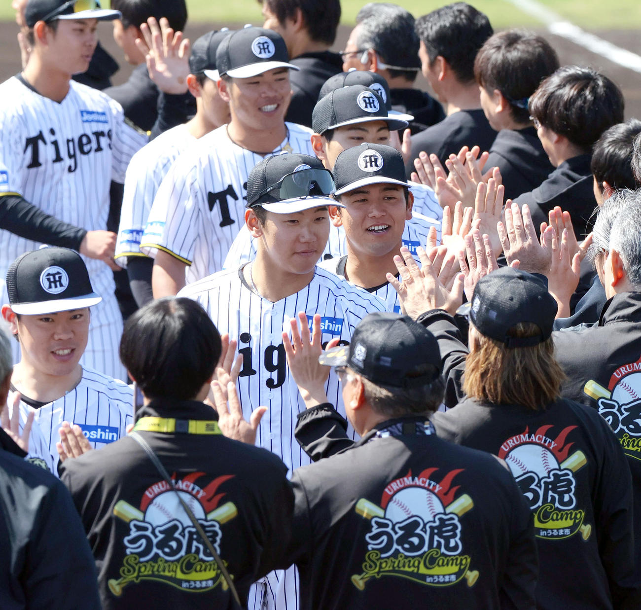 具志川キャンプを打ち上げ、関係者とハイタッチする阪神門別（左から2人目）ら（撮影・上山淳一）