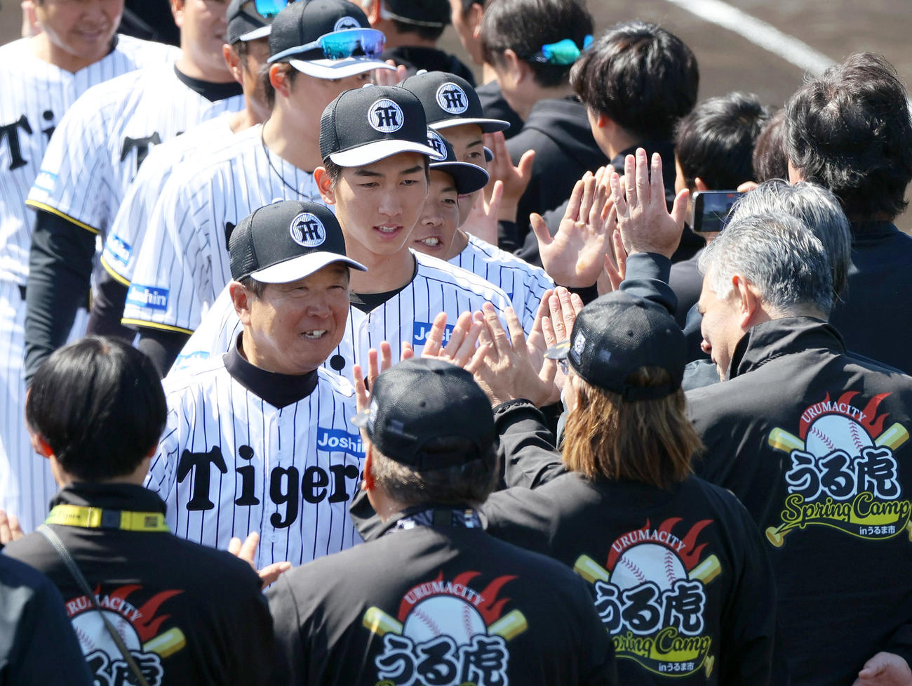 具志川組はキャンプ打ち上げで関係者とハイタッチする阪神平田2軍監督（左）、今朝丸（左から2人目）ら（撮影・上山淳一）