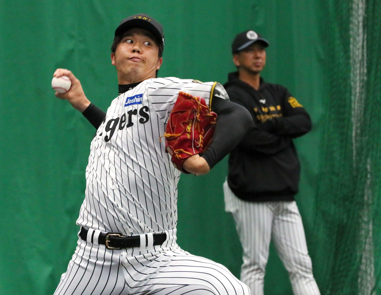ブルペンで投球する阪神才木浩人。奥は藤川球児監督（2025年2月21日撮影）