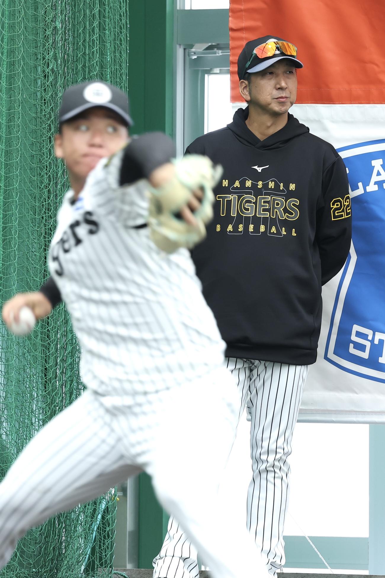 ブルペンで阪神村上（手前）の投球練習を見守る藤川監督（撮影・前田充）