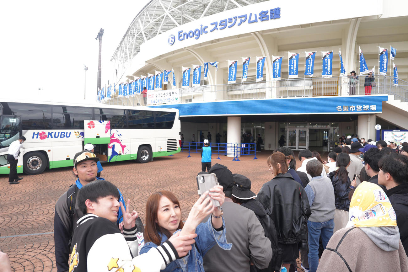 キャンプを打ち上げ、バス乗車前にファンサービスする日本ハム伊藤（左端）（撮影・足立雅史）