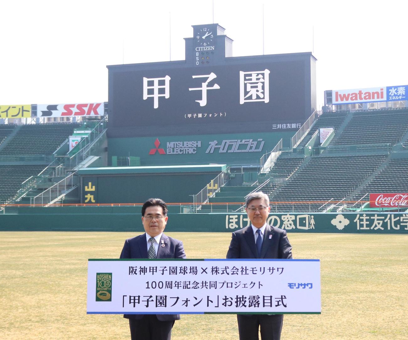 甲子園フォントで表示されたスコアボードを前に記念撮影する阪神電鉄谷本修取締役（左）と株式会社モリサワの森沢彰彦代表取締役社長（撮影・林亮佑）