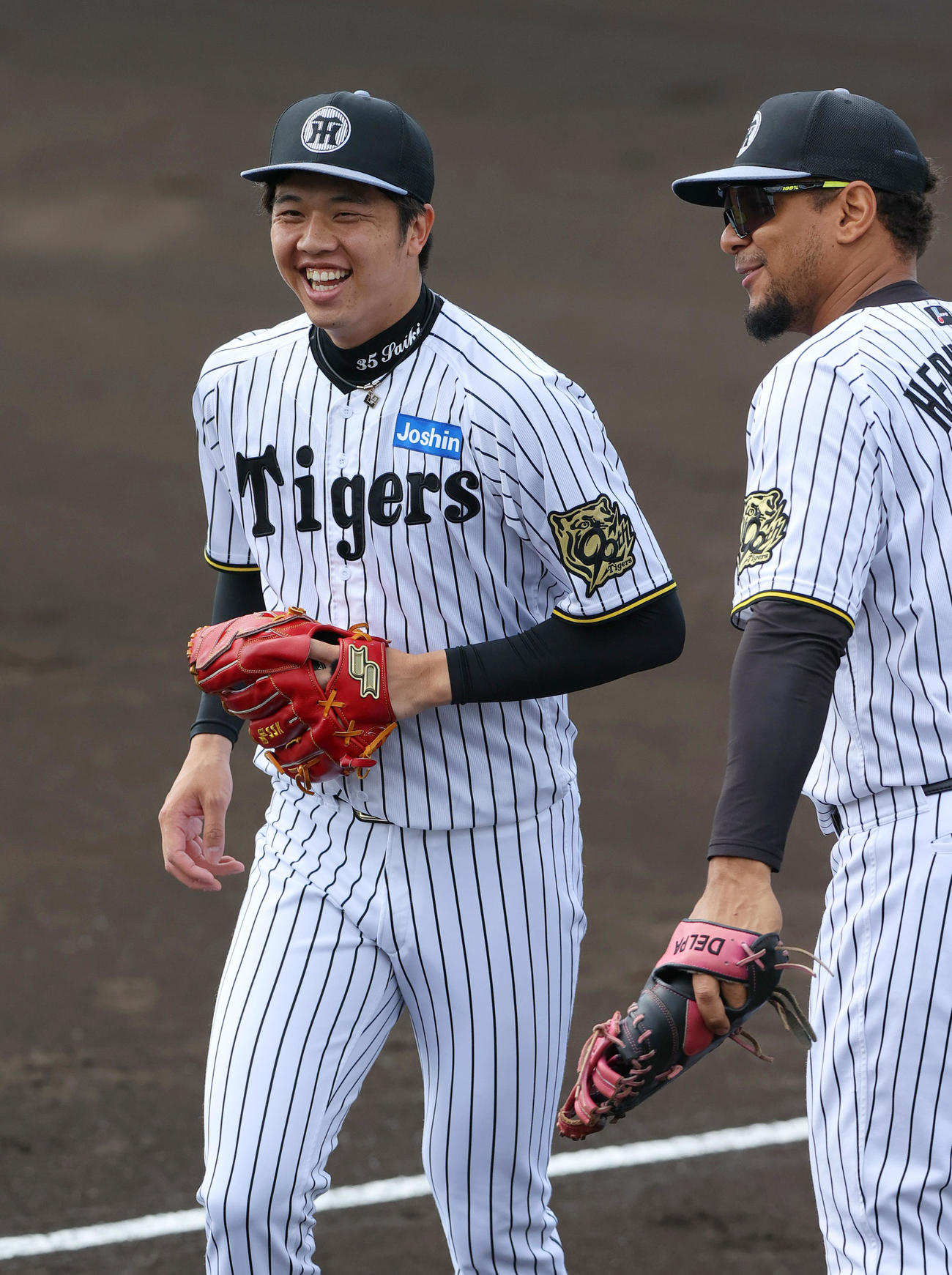 阪神才木（左）は投内連係で笑顔を見せる。右はヘルナンデス（撮影・上山淳一）