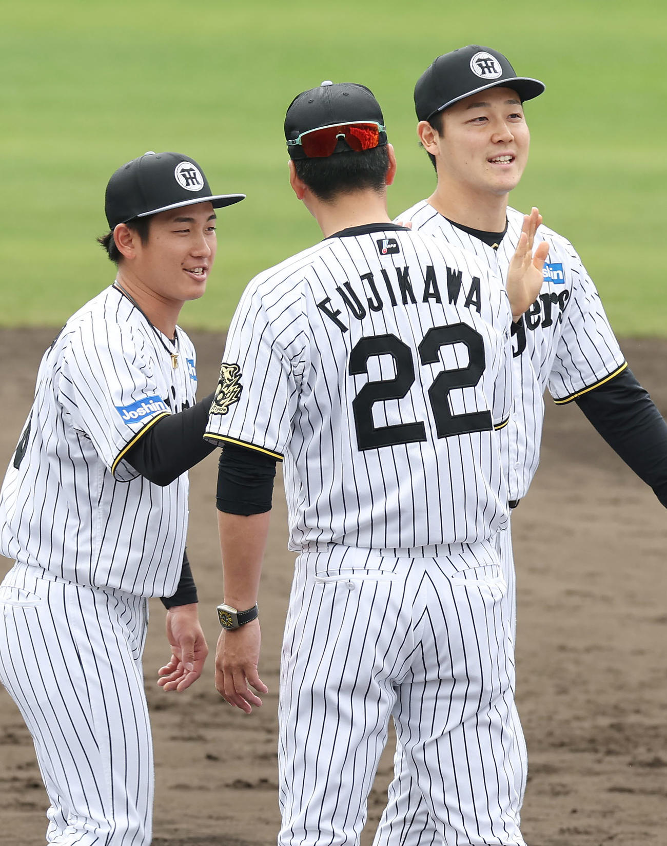 春季キャンプを打ち上げ、阪神藤川監督（中央）とタッチを交わす伊原（左）と木下（撮影・前田充）