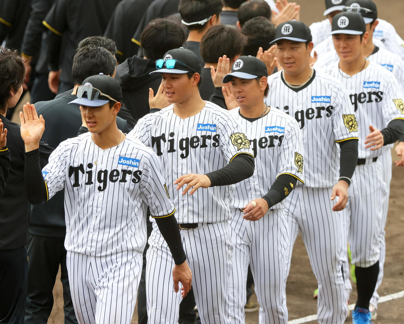 春季キャンプを打ち上げ、スタッフらとタッチをかわす、左から阪神小幡、森下、梅野、大山、豊田ら（撮影・上山淳一）