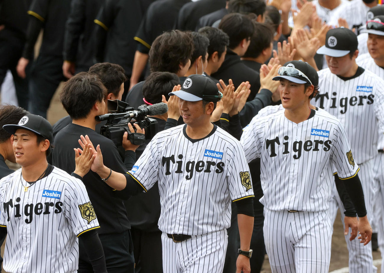 春季キャンプを打ち上げ、スタッフらとタッチをかわす、左から阪神伊原、藤川監督、高寺ら（撮影・上山淳一）