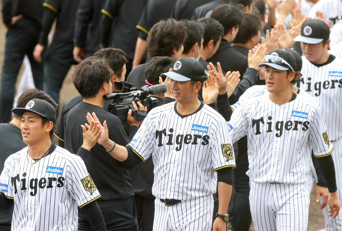 春季キャンプを打ち上げ、スタッフらとタッチをかわす、左から阪神伊原、藤川監督、高寺（撮影・上山淳一）