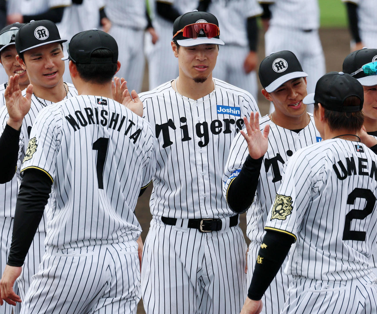 宜野座キャンプを終え森下（左）らナインとタッチする佐藤輝（撮影・加藤哉）