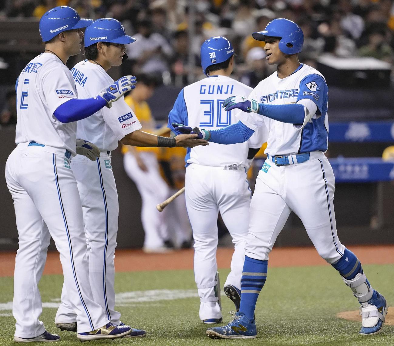 2回、先制3ランを放ち野村（左から2人目）らとタッチを交わす日本ハム万波（共同）