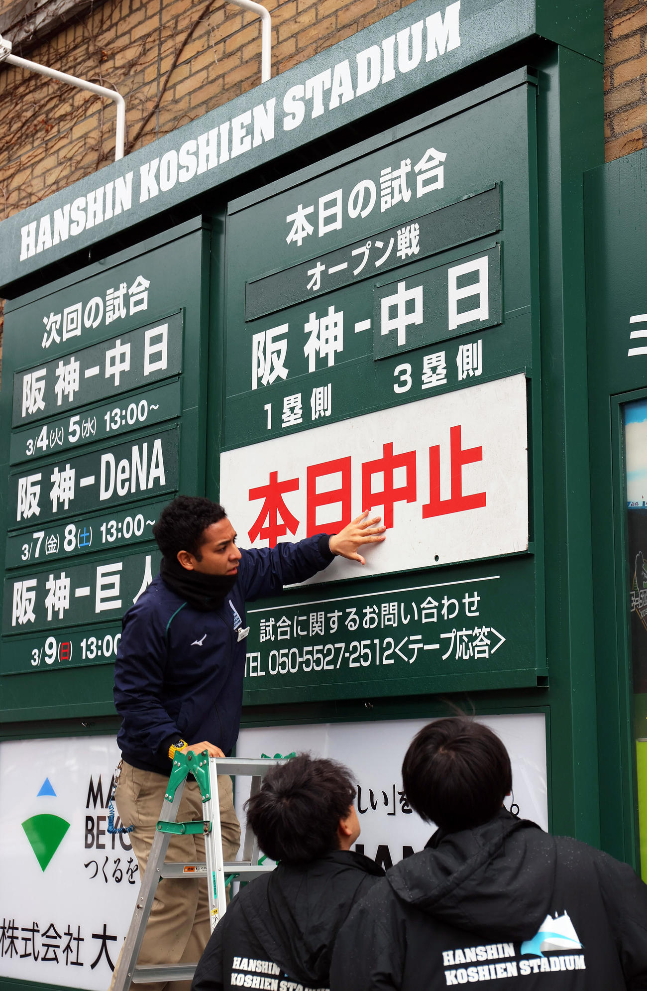 オープン戦・阪神対中日　雨天中止となり看板を設置する甲子園球場の職員たち（撮影・上山淳一）