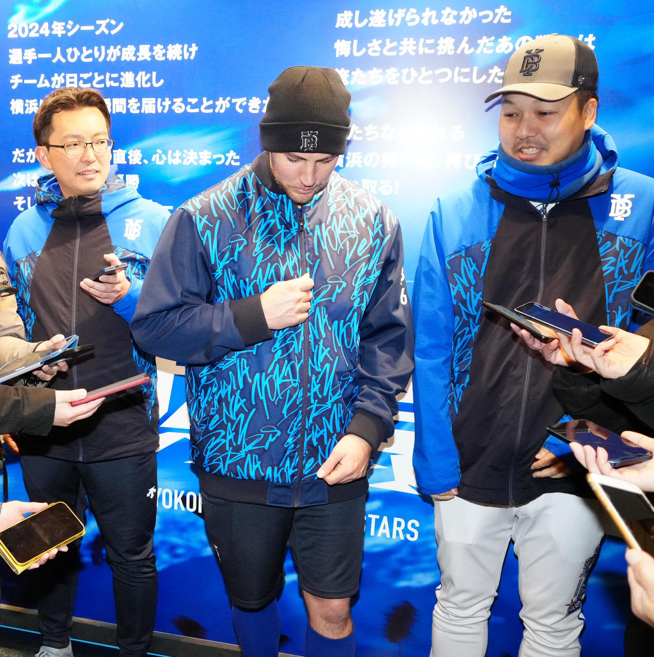 DeNA対広島　練習後、取材に応じ、上着のファスナーを上げるしぐさを見せるDeNAバウアー（中央）（撮影・江口和貴）