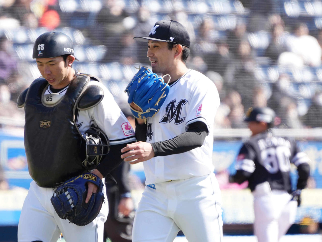 オープン戦・ロッテ対ソフトバンク　1回ソフトバンク打線を3者連続三振に仕留めたロッテ先発の小島は寺地（左）と談笑しながらベンチへ引き揚げる（撮影・小沢裕）