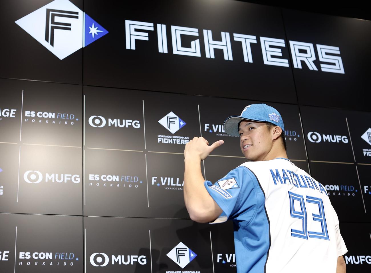 背番号「93」を指差し写真に納まる日本ハム松岡（撮影・河田真司）