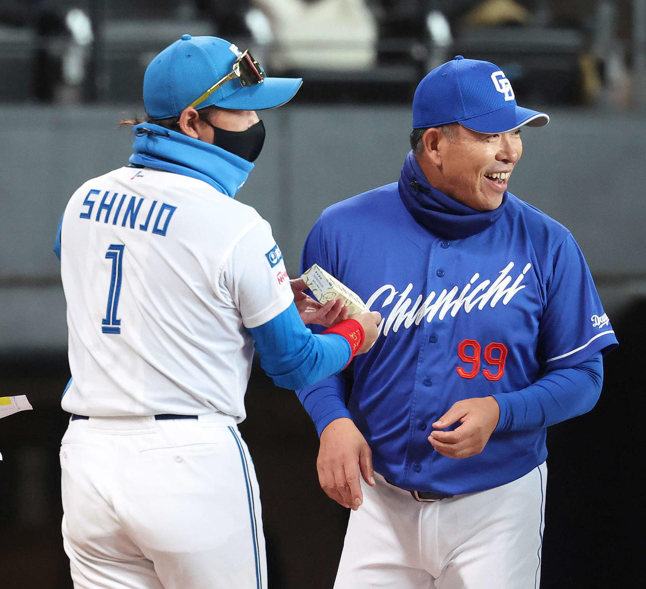 日本ハム対中日　開始前、メンバー表交換で日本ハム新庄監督（左）に「きよめぱん」を渡す中日井上監督（撮影・河田真司）