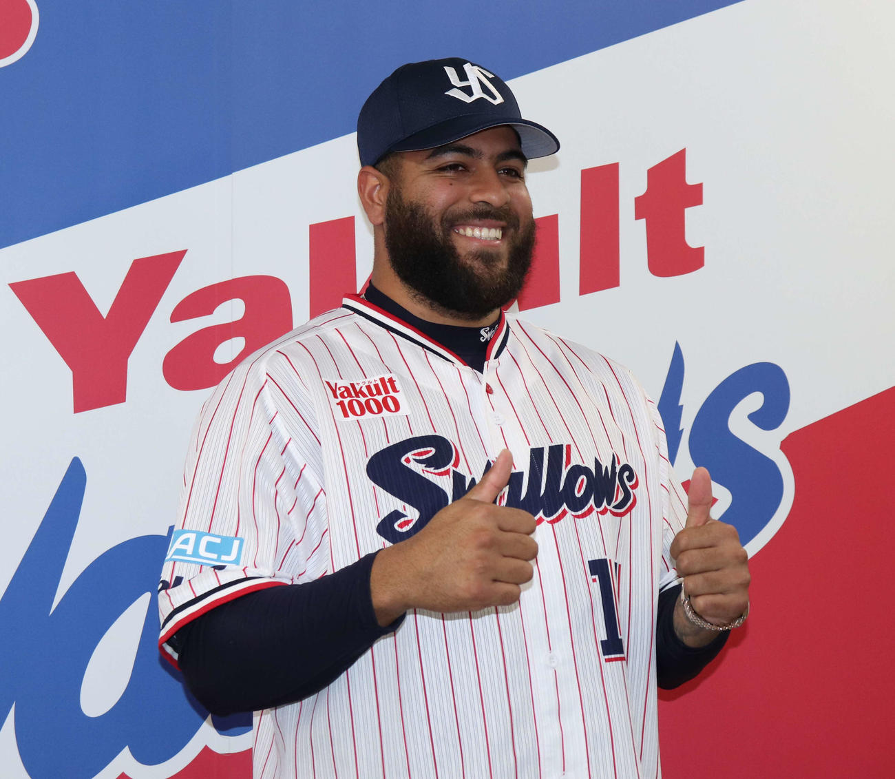 都内で行われたヤクルト入団会見で笑顔でグーポーズを見せるアビラ（撮影・佐瀬百合子）