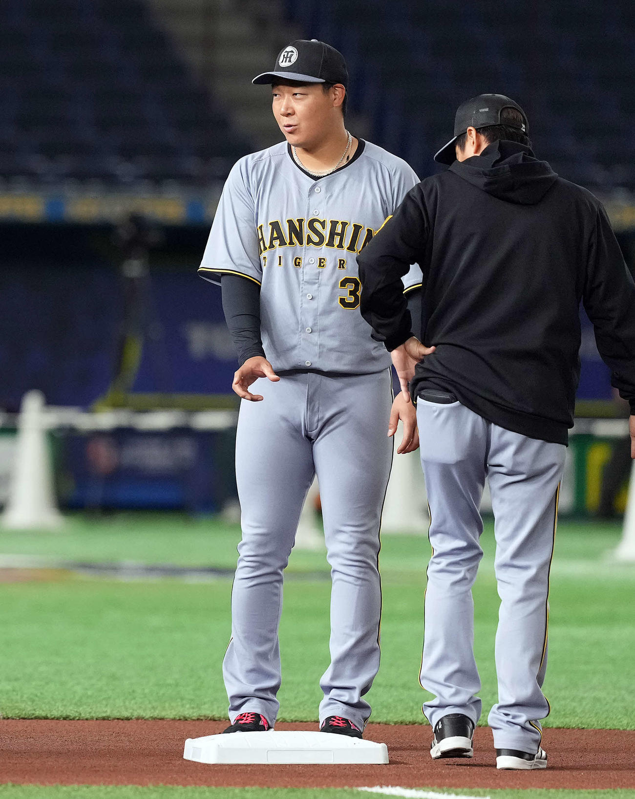 MLB使用の一塁ベースを見て関係者と話をする阪神大山（撮影・たえ見朱実）