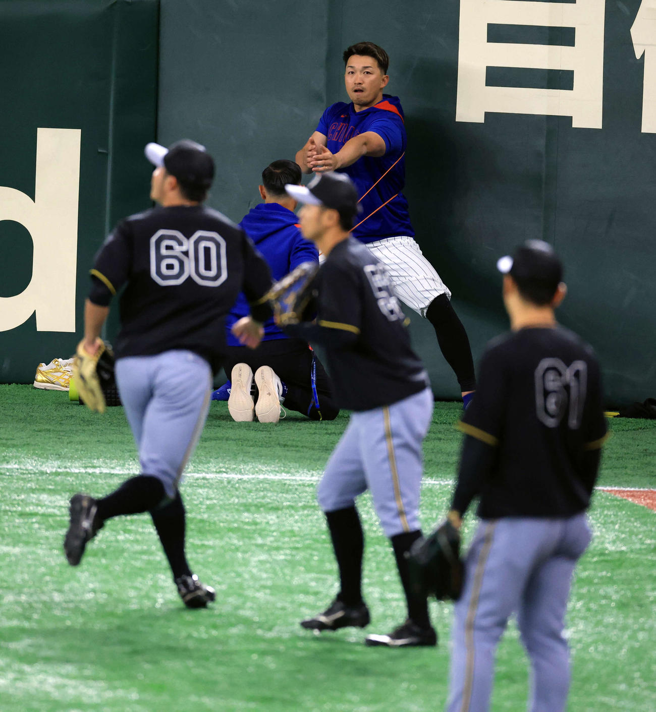 阪神対カブス　試合前練習をする阪神の選手たちを見ながらウオームアップするカブス鈴木（撮影・浅見桂子）