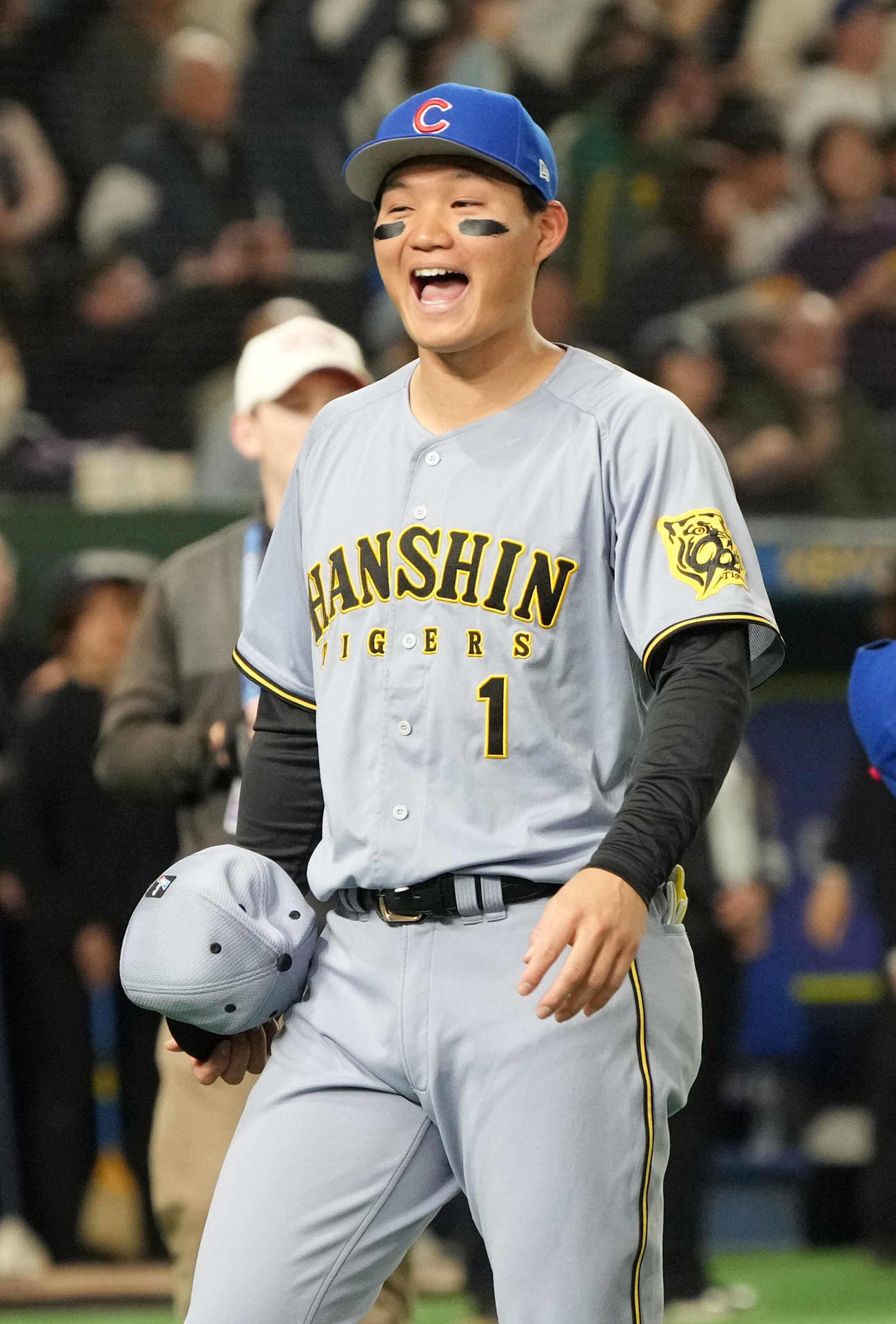阪神対カブス　試合前のセレモニーで交換したカブスの帽子をうれしそうに被る阪神森下（撮影・小沢裕）