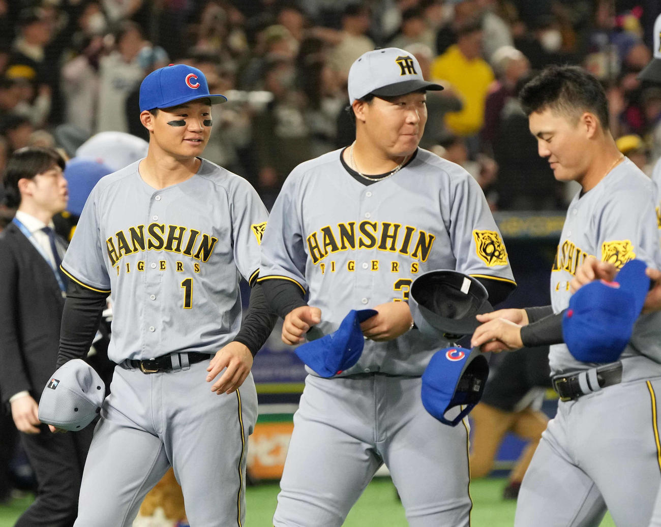 阪神対カブス　試合前のセレモニーで交換したカブスの帽子をうれしそうに被る阪神森下。右へ大山、前川（撮影・小沢裕）