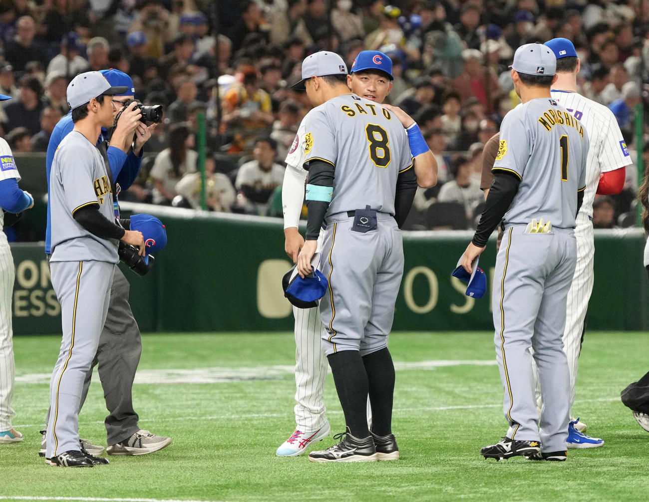 阪神対カブス　試合前のセレモニーでカブス鈴木から声を掛けられる阪神佐藤輝（中央）。左は近本、右は森下（撮影・小沢裕）