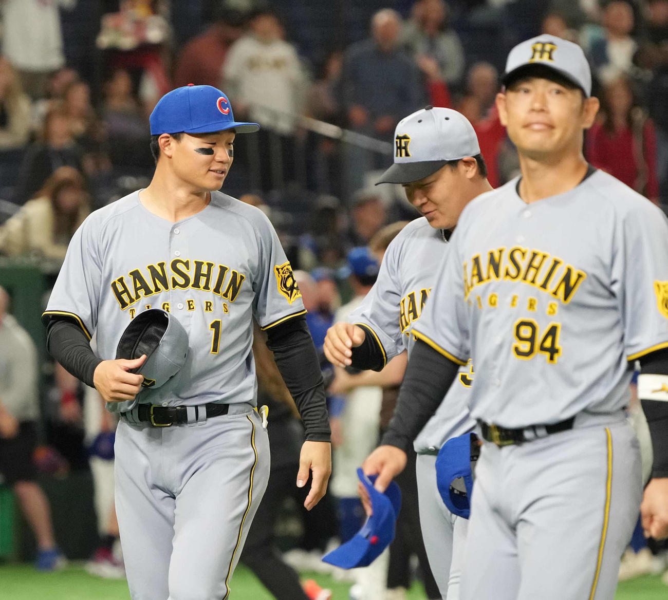 阪神対カブス　試合前のセレモニーで交換したカブスの帽子をうれしそうに被る阪神森下。右は大山（撮影・小沢裕）