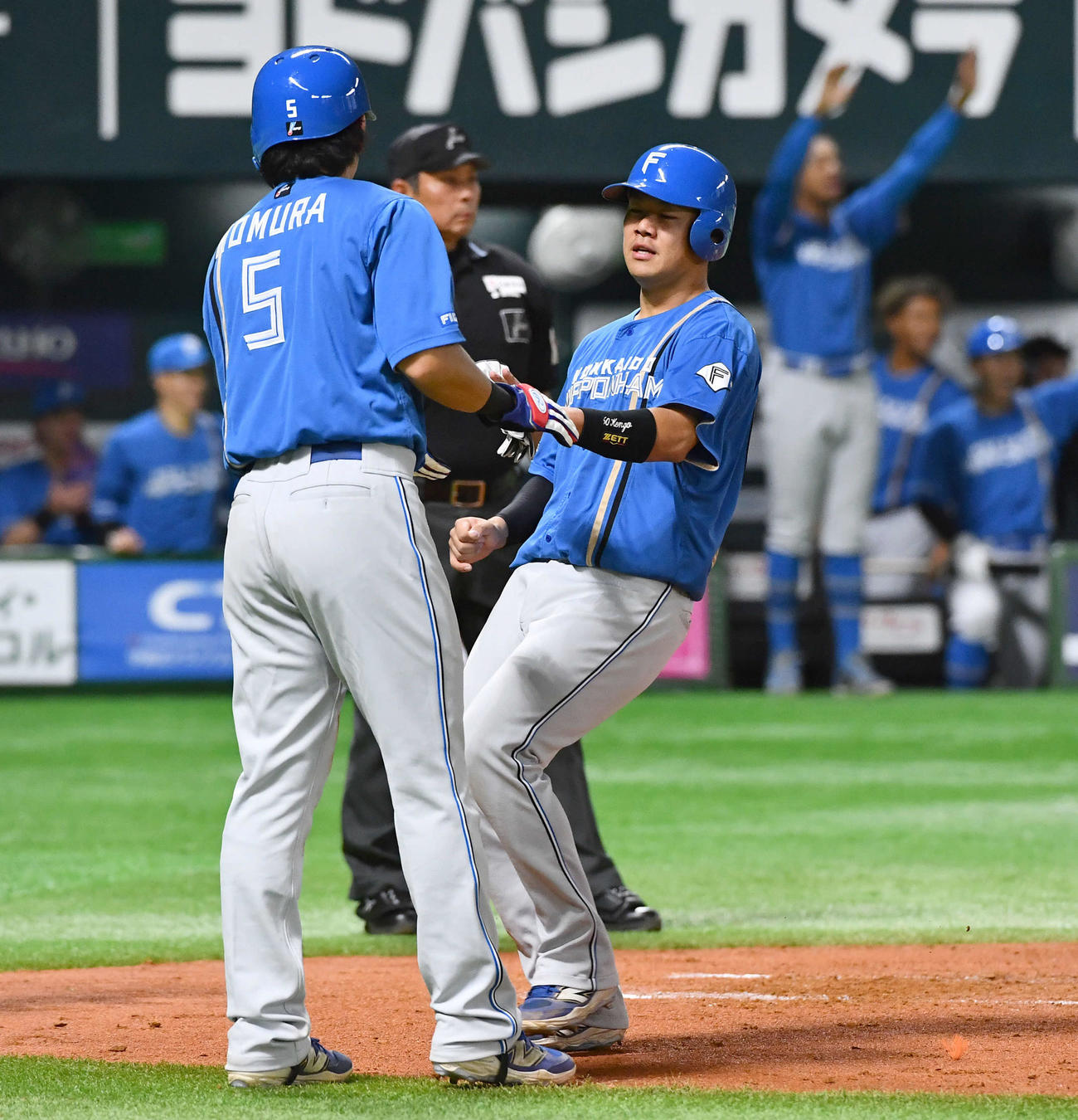 ソフトバンク対日本ハム　2回表日本ハム1死二、三塁、石井の先制2点適時右二塁打で生還し、野村（左）とタッチを交わす吉田（撮影・岩下翔太）