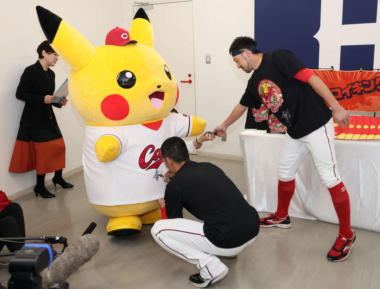 ポケモンセンター広島のリニューアルオープンを記念して、カープがコラボ。ピカチュウのユニホームにサインする矢野（中央）と菊池（撮影・加藤孝規）