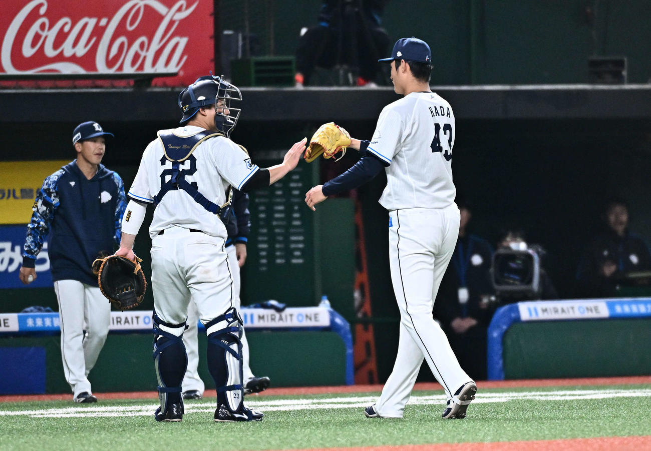 西武対DeNA 4回表DeNA2死一、二塁、筒香を空振り三振に仕留めた羽田（右）は古賀悠とタッチをかわす（撮影・滝沢徹郎）