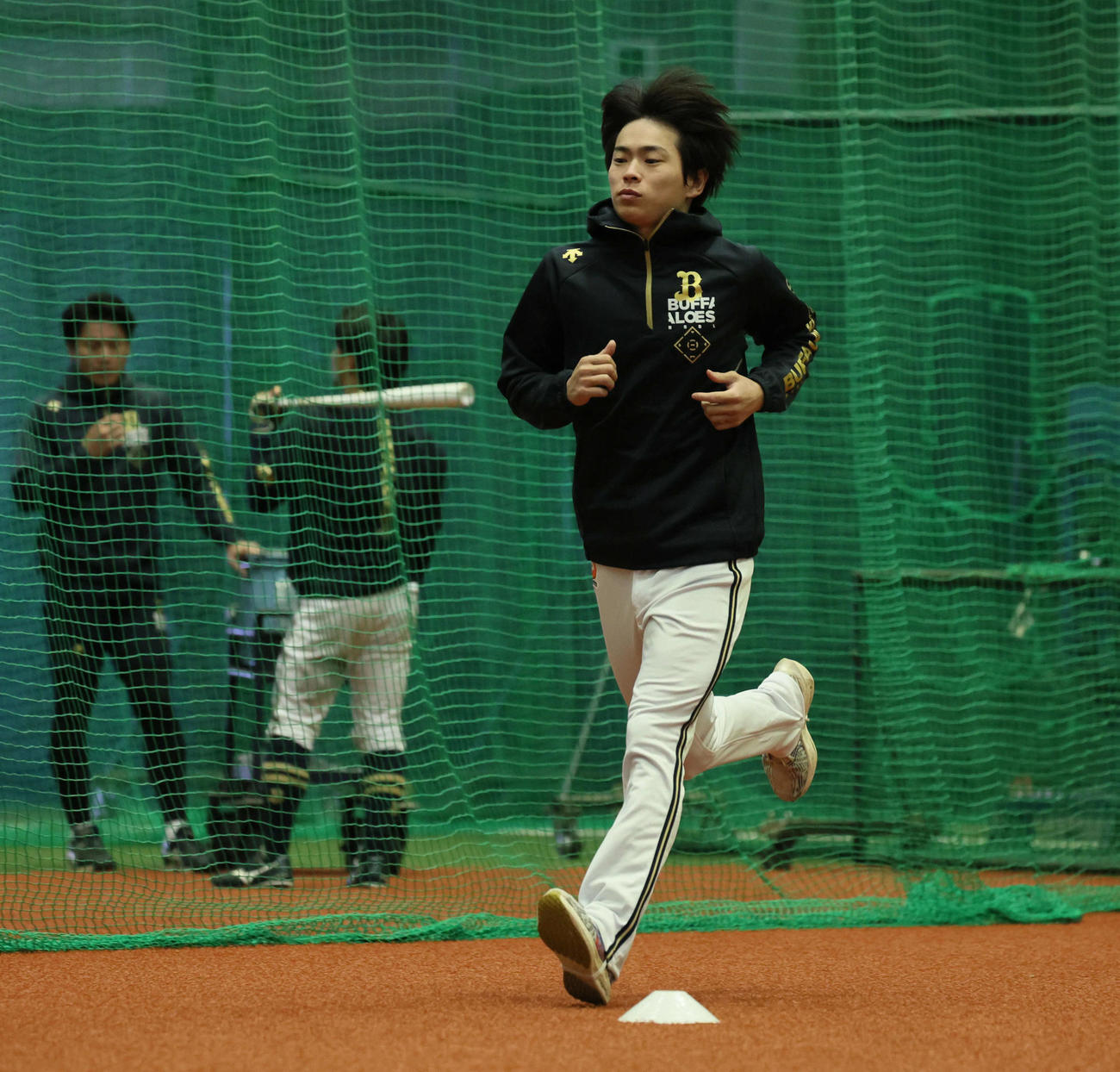 ナインが練習する室内練習場入りし、ランニングするオリックス山岡（撮影・宮崎幸一）
