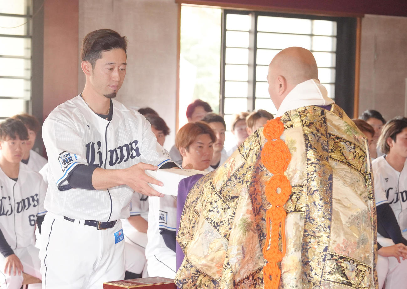 狭山山不動寺で必勝祈願を行い、お守りを受け取る西武外崎（撮影・足立雅史）